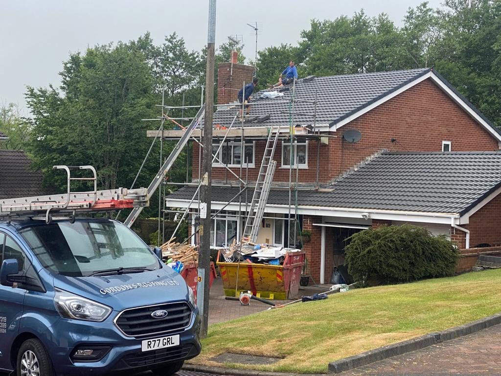 Blue Gordon’s Roofing Ltd van outside a brick house with scaffolding and a new tiled roof